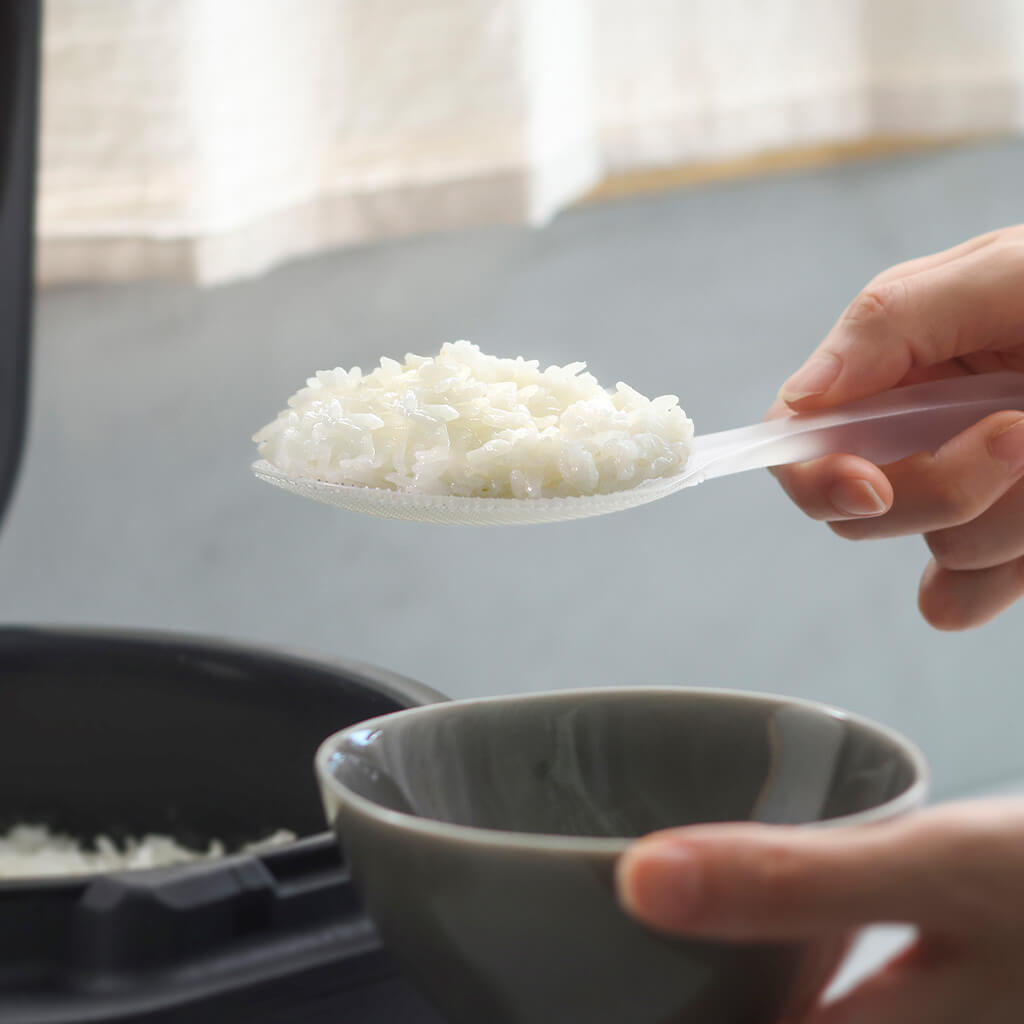 Hands serving rice with the clear Marna premium standing rice paddle