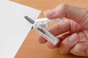 Hand cutting paper with white Midori XS compact scissors